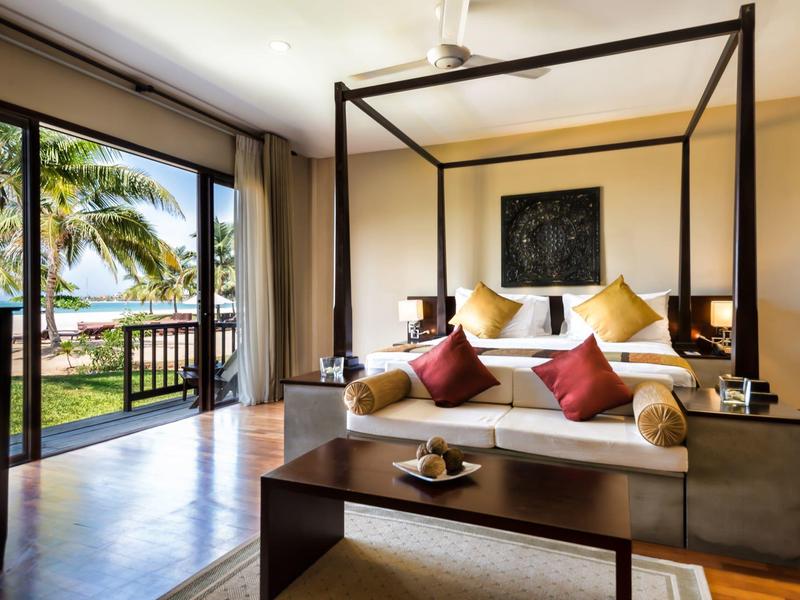 Chambre d'hôtel moderne avec lit à baldaquin et vue sur la mer à travers de grandes fenêtres en verre