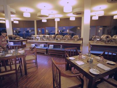 Przytulna restauracja z przyciemnionym oświetleniem i nakrytymi stolikami z widokiem na miasto.