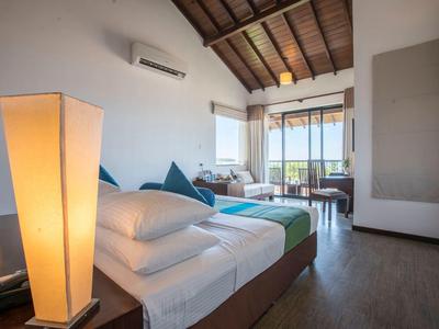 Nowoczesny pokój hotelowy z podwójnym łóżkiem, wygodnymi poduszkami i widokiem na balkon i przyrodę.