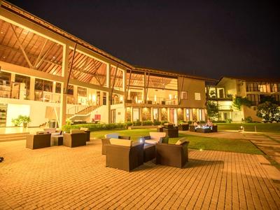 Osvětlený venkovní hotel s posezením a zelenými plochami v noci.