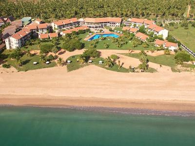 Widok z lotu ptaka na ośrodek nadmorski z basenem, terenami zielonymi i bezpośrednim dostępem do morza.