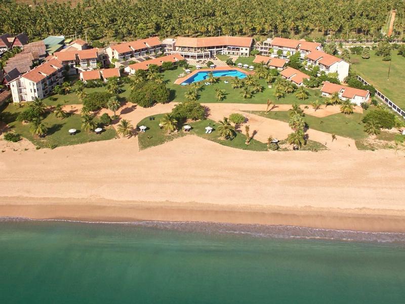 Widok z lotu ptaka na ośrodek nadmorski z basenem, terenami zielonymi i bezpośrednim dostępem do morza.