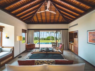 Luxuriöses Zimmer mit Holzdach, großen Fenstern und Blick auf einen Pool und Palmen.