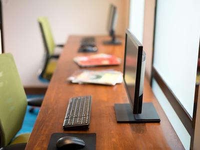 Moderner Arbeitsplatz mit Computer, Tastatur und Maus auf Holztisch in einem hellen Büro.