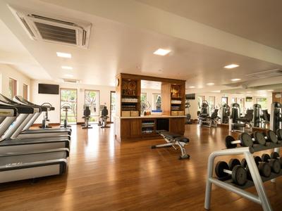 Moderner Fitnessraum mit Holzboden, Trainingsgeräten und Gewichten in einem Hotel.