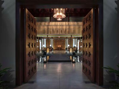 Offene Holztüren führen zu einem eleganten, modernen Innenraum mit Sitzgelegenheiten und gedämpfter Beleuchtung.