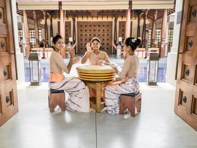 Drei Frauen sitzen in traditioneller Kleidung an einem runden Tisch in einem offenen, dekorativen Raum.