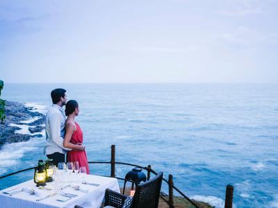Paar steht am Geländer mit Blick auf das Meer bei ruhiger, bewölkter Atmosphäre.