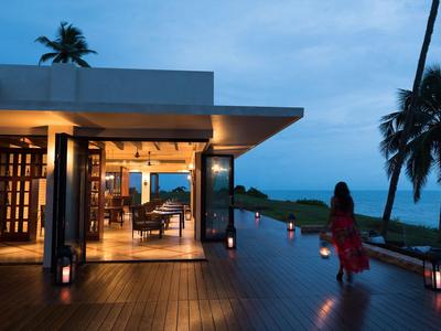 Abendaufnahme eines modernen Hauses mit Terrasse und Blick auf das Meer, Person geht am Rand entlang.