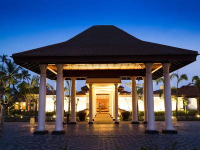 Beleuchteter Pavillon mit weißem Gebäude und Palmen bei Dämmerung