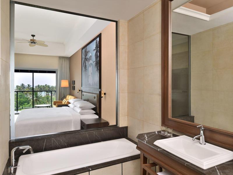 Bagno moderno con vasca, lavabo e vista sulla camera da letto con balcone.