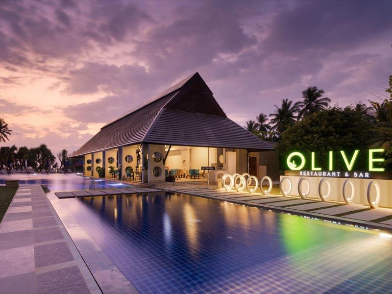 Resort di lusso con piscina illuminata e architettura moderna al tramonto.