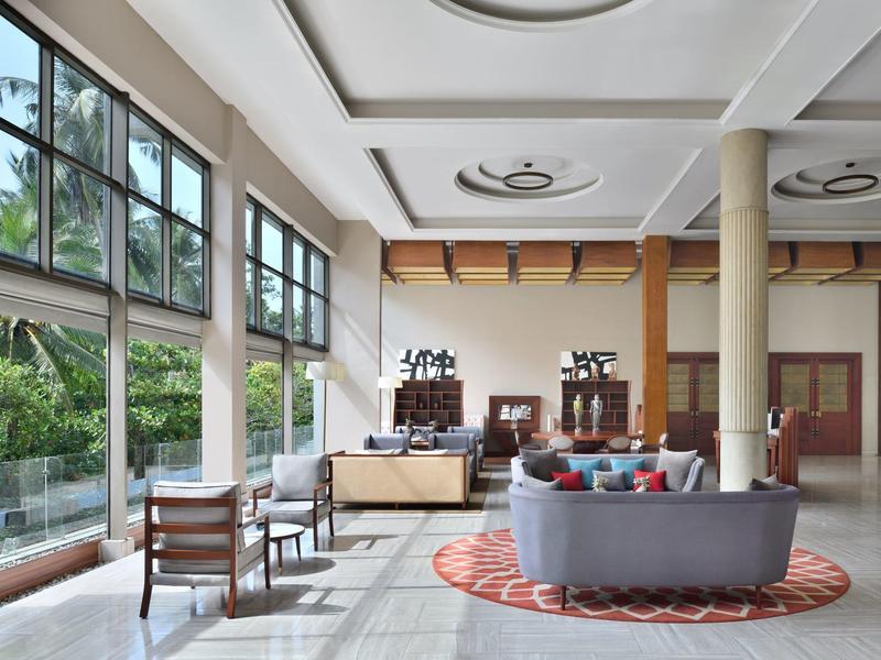 Luminosa hall dell'hotel con ampie finestre, area salotto e arredi moderni.