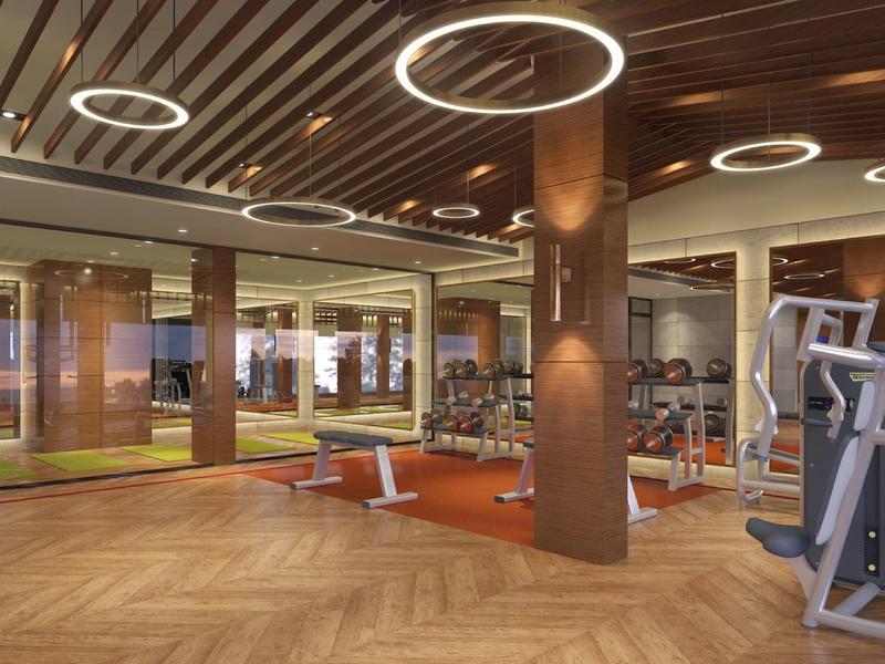Palestra moderna con pavimento in legno, area pesi e luci circolari sul soffitto.