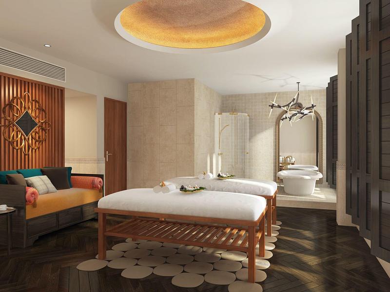 Camera d'hotel elegante con lettino da massaggio, divano, specchio e luce soffusa al soffitto.