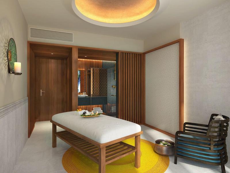 Sala benessere moderna con lettino per massaggi, illuminazione e zona salotto in design luminoso.