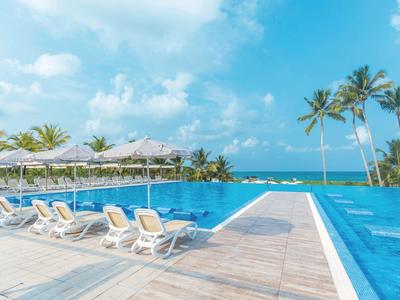Piscina vicino al mare con sdraio e cielo azzurro.