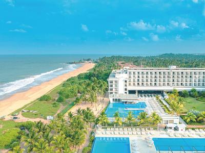 Hotel sul mare con piscine e spiaggia sabbiosa circondata da palme.