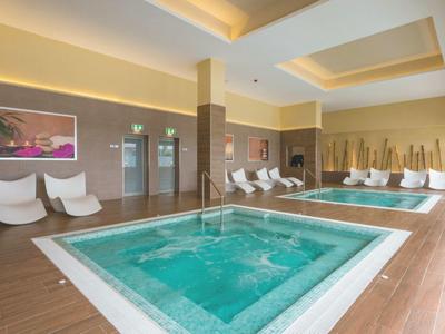 Area interna con piscine riscaldate, sedie a sdraio e illuminazione soffusa.