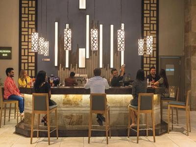 Bar elegante con lampade sospese e clienti seduti su sgabelli di legno.