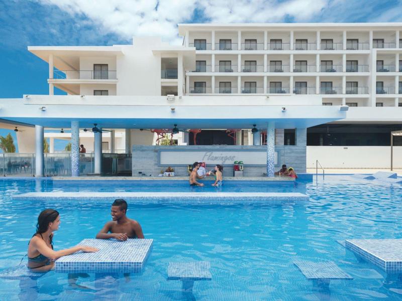 Piscina con bar in hotel moderno sotto un cielo parzialmente nuvoloso.
