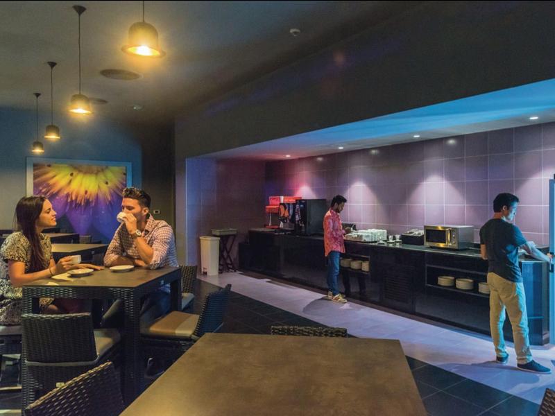 Interno di un caffè moderno con clienti e illuminazione soffusa.