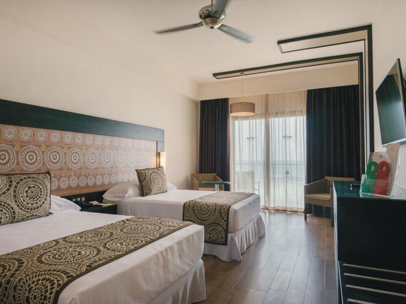 Camera d'hotel moderna con due letti singoli, balcone e design sobrio.