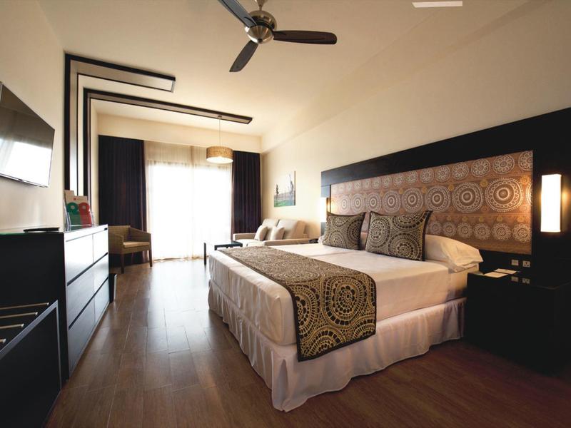 Camera d'hotel moderna con letto grande, TV a parete e balcone luminoso.