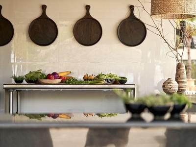 Moderne rustikale Küche mit Wandschneidebrettern und frischem Gemüse auf dem Tisch.
