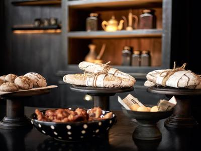 Verschiedene Brotsorten auf dunklem Tisch mit rustikaler Kücheneinrichtung im Hintergrund.