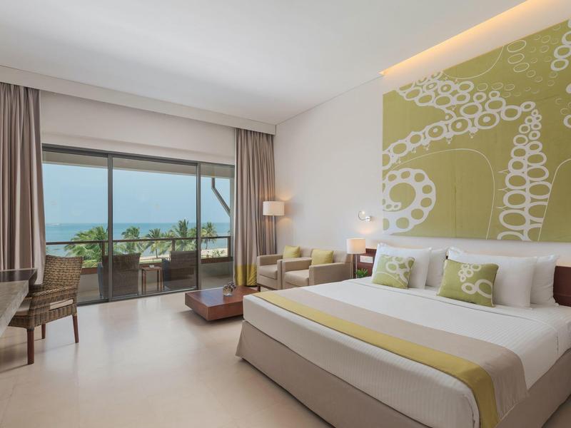 Modern eingerichtetes Hotelzimmer mit großem Bett und Terrasse mit Meerblick.