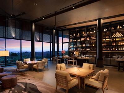Moderní hotelový lounge s velkými okny a teplou atmosférou při západu slunce.