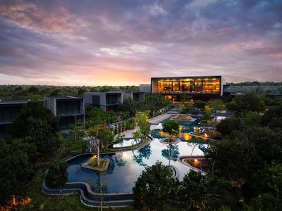 Luxusní hotel s osvětleným bazénem a moderní architekturou při západu slunce.