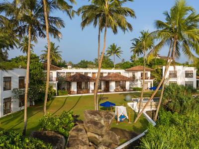 Luxuriöses Hotel mit weißen Gebäuden, umgeben von grünen Palmen und gepflegtem Rasen.