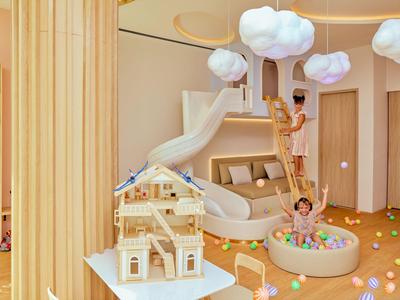Speelruimte voor kinderen met netschommel, glijbaan en ballenbak in lichte, moderne kamer.