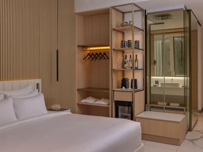 Moderne hotelkamer met bed, open kledingkast en spiegelwand.