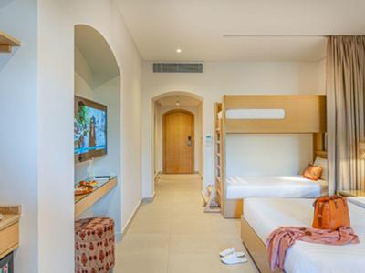 Hell eingerichtetes Hotelzimmer mit zwei Betten, einem Etagenbett und moderner Dekoration.