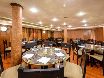 Elegantes Restaurant mit runden Tischen, Stühlen und warmem Holzdekor.