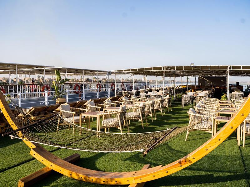 Terrasse extérieure avec chaises, tables et hamacs sous un ciel dégagé.