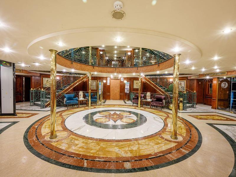 Elegant hotel lobby area with marble flooring and gold-colored stair railings.