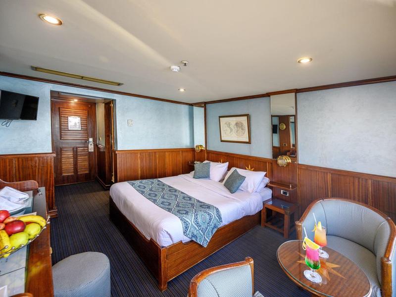 Cozy hotel room with double bed, seating area, and fresh fruit on the table.