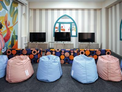 Kinderspeelruimte met zitzakken, tv's en kleurrijke muurschilderingen in een gezellige kamer.