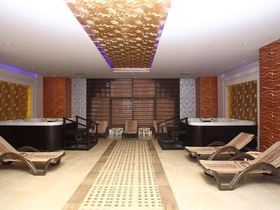 Luxe spa kamer met meerdere bubbelbaden, houten ligstoelen en sfeerverlichting.