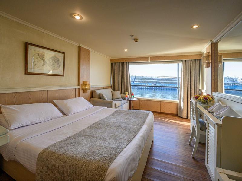 Modern hotelkamer met groot bed, zeezicht en gezellige zithoek.