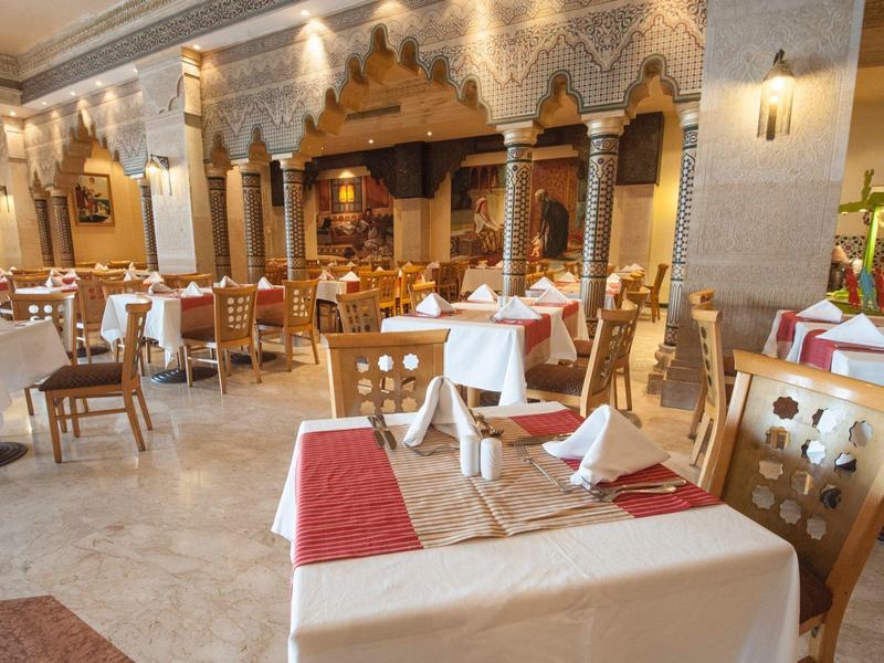 Elegant restaurant met houten stoelen, witte tafelkleden en warme verlichting in een ruime kamer.