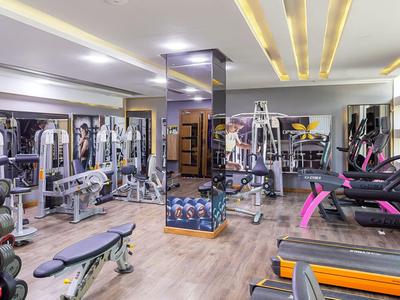 Moderner Fitnessraum mit Trainingsgeräten, Hanteln und Laufbändern in einem Hotel.