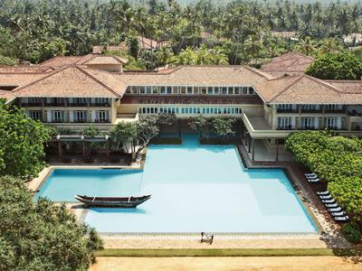 Großes Hotel mit großzügigem Pool und Boot in tropischer Umgebung.