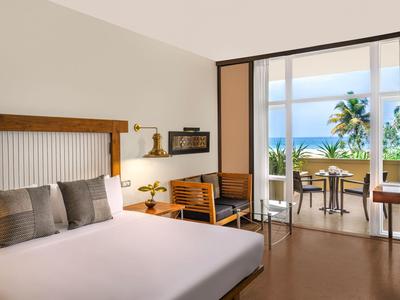 Modern eingerichtetes Hotelzimmer mit Doppelbett und Balkon mit Meerblick.