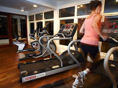 Frau läuft auf einem Laufband in einem modernen Fitnessraum mit mehreren Geräten.