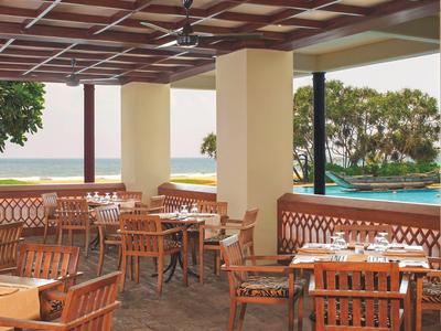 Offener Essbereich mit Holzmöbeln, Deckenventilatoren, Blick auf Pool und Meer